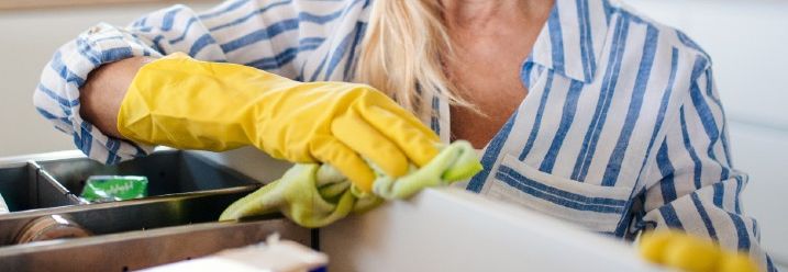 Frau putzt Küchenschrank von innen